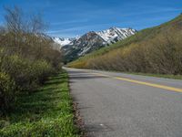 the road is paved with yellow markings and has a snowy mountain range in the background