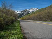 the road is paved with yellow markings and has a snowy mountain range in the background