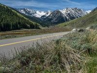 the road is paved with yellow markings and has a snowy mountain range in the background