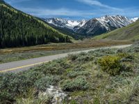 the road is paved with yellow markings and has a snowy mountain range in the background