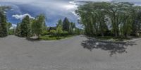 a road is shown through a fish eye lens on a cloudy day with a house in the distance