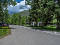 an empty street lined with trees and a mountain range in the distance in the back