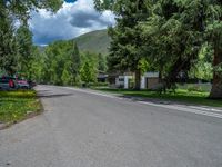 an empty street lined with trees and a mountain range in the distance in the back