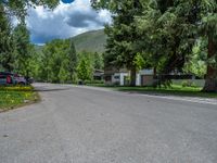 an empty street lined with trees and a mountain range in the distance in the back