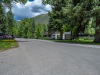 an empty street lined with trees and a mountain range in the distance in the back