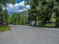 an empty street lined with trees and a mountain range in the distance in the back