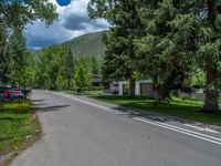 an empty street lined with trees and a mountain range in the distance in the back