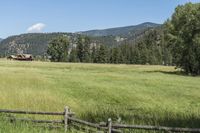 a field that is near the fence of a farm in a rural country setting with mountains behind it