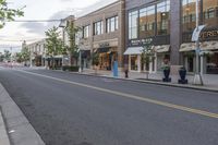 an empty city street and street sign in the distance is a tree with a potted flower in it