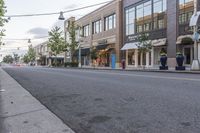 an empty city street and street sign in the distance is a tree with a potted flower in it