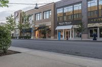 an empty city street and street sign in the distance is a tree with a potted flower in it