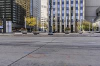 an empty sidewalk in a large city with glass windows on each side and traffic lights in the middle