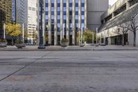 an empty sidewalk in a large city with glass windows on each side and traffic lights in the middle