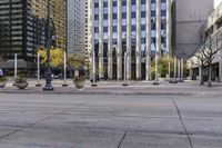 an empty sidewalk in a large city with glass windows on each side and traffic lights in the middle