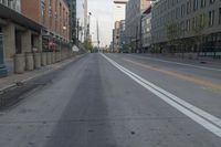 an empty road with a few tall buildings and a car driving down the street by