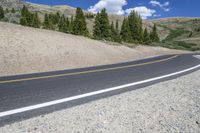 the empty winding road curves into the distance between mountains and trees of the nearby area