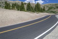 the empty winding road curves into the distance between mountains and trees of the nearby area