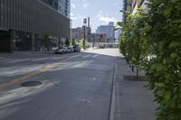 a city street with cars parked in front of the buildings and the sidewalk is empty, on a sunny day