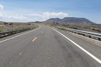 a highway in a hilly area with mountains in the background, and an exit sign