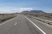 a highway in a hilly area with mountains in the background, and an exit sign