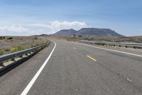 a highway in a hilly area with mountains in the background, and an exit sign