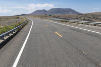 a highway in a hilly area with mountains in the background, and an exit sign