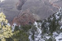 skiers ride through the snow - capped landscape of an expanse of mountains with trees and rocks