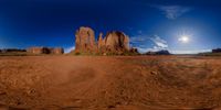 a wide angle view of mountains from a dirt road near to a body of water