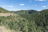 scenic area with steep mountains and pine trees, in the background are rolling hills and valleys