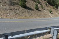 a motorcycle is sitting on the side of a road next to a guardrail as a mountain passes by