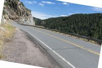 a road with a mountain next to it and a treeline at the top of one side