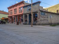 a red fire hydrant sitting in front of an old store window and building next to an open air field