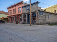 a red fire hydrant sitting in front of an old store window and building next to an open air field