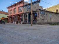 a red fire hydrant sitting in front of an old store window and building next to an open air field