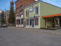 a red fire hydrant sitting in front of an old store window and building next to an open air field