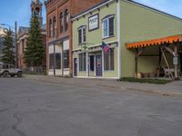 a red fire hydrant sitting in front of an old store window and building next to an open air field