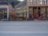 a red fire hydrant sitting in front of an old store window and building next to an open air field