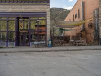 a red fire hydrant sitting in front of an old store window and building next to an open air field