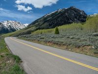 the road is paved with yellow markings and has a snowy mountain range in the background