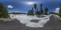 the view looking into the distance of a snow covered area with trees and dirt near a road