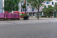 a bench is painted in pink and purple in the middle of an empty city street