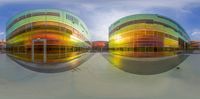 a colorful building reflecting another with its large windows in front of it, and below it is the water