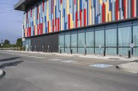 a picture of the street outside a multi - color building with markings on it's parking spaces