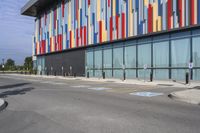 a picture of the street outside a multi - color building with markings on it's parking spaces