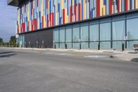 a picture of the street outside a multi - color building with markings on it's parking spaces