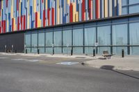 a picture of the street outside a multi - color building with markings on it's parking spaces