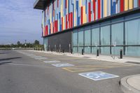 a picture of the street outside a multi - color building with markings on it's parking spaces