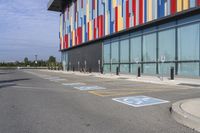 a picture of the street outside a multi - color building with markings on it's parking spaces