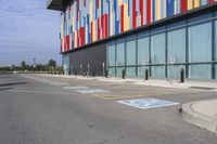 a picture of the street outside a multi - color building with markings on it's parking spaces