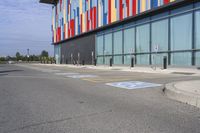 a picture of the street outside a multi - color building with markings on it's parking spaces